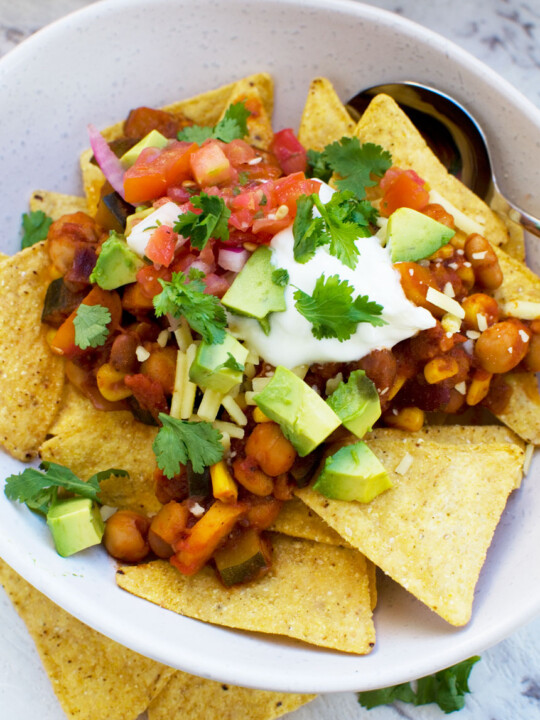 Closeup of 5 bean loaded nachos in a white bowl from above