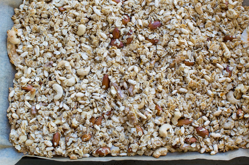 Ingredients for homemade granola scattered on a baking tray ready for the oven