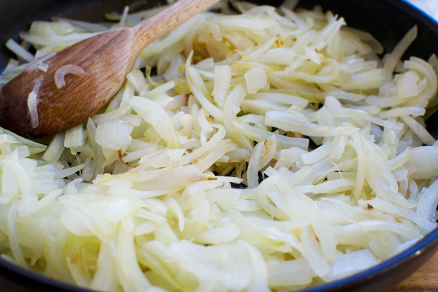 frying onions in a pan for Greek baked fish