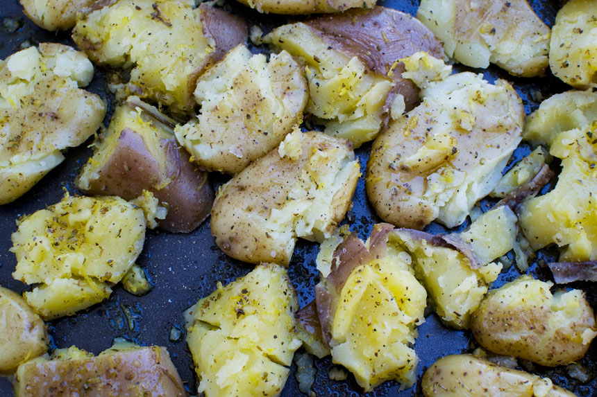Smashed potatoes ready for baking on a baking tray