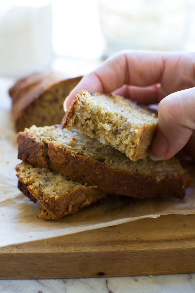 Someone picking up a slice of mini banana bread with other slices in the background