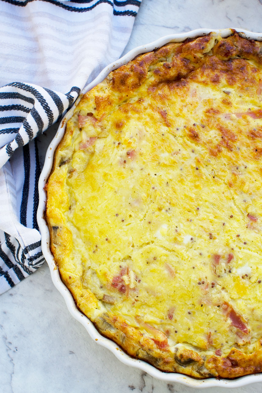 A crustless quiche or impossible quiche just out of the oven from above with a blue striped tea towel