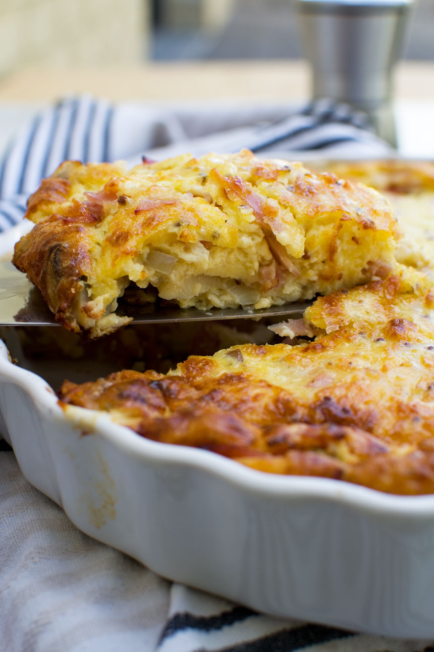 Someone lifting a piece of crustless quiche out of a white dish