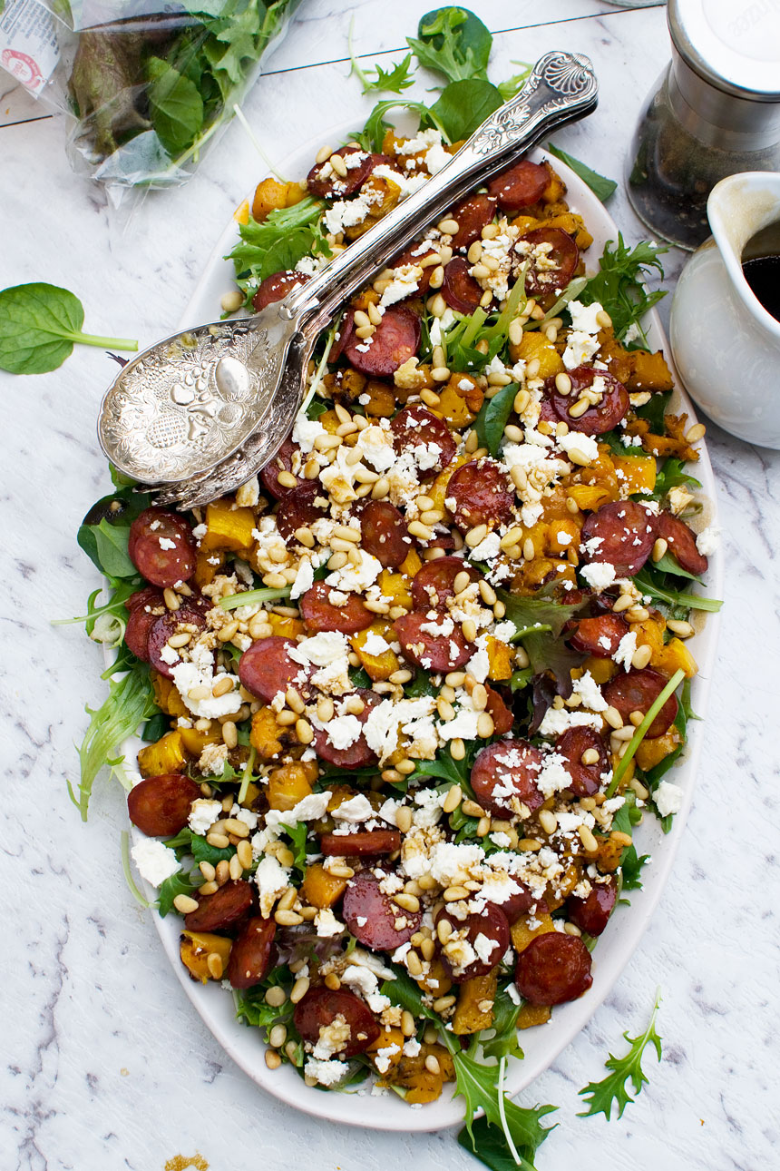 Warm roasted pumpkin, chorizo and feta salad on an oval plate and with servers in it from above