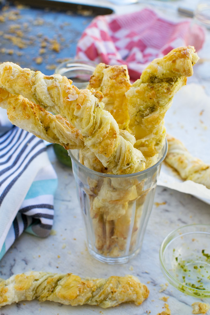 Supermarket copycat pesto and cheese twists piled into a glass with a blue tea towel in the background