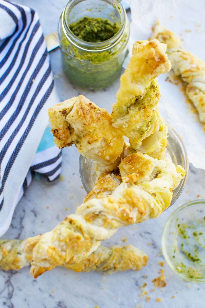 A close up of supermarket copycat pesto and cheese twists piled into a glass from above