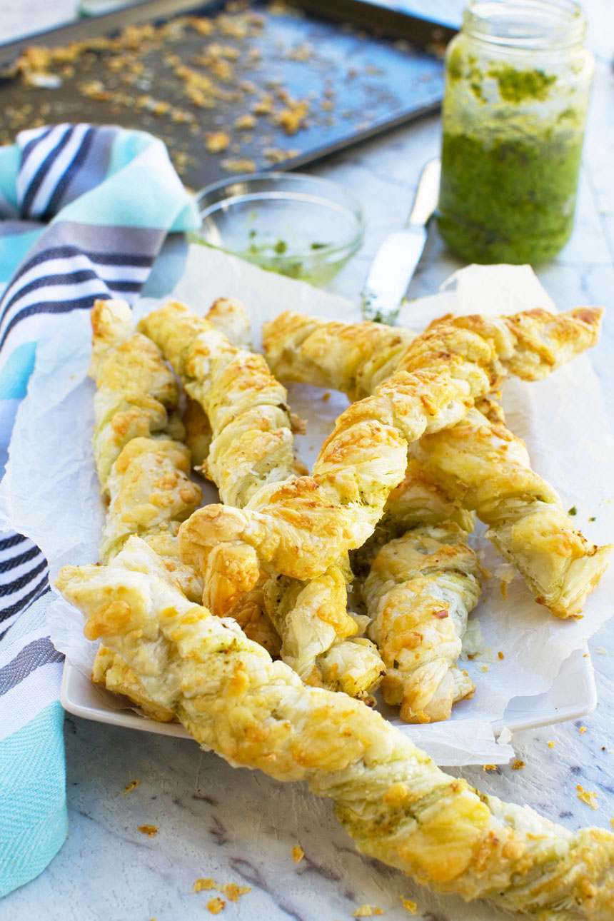 Supermarket copycat pesto and cheese twists on a white plate with a blue tea towel in the background