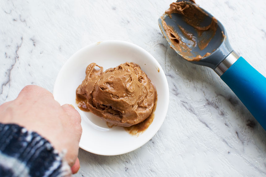 Someone holding 5-minute chocolate banana ice cream with an ice cream scoop in the background