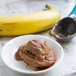 5-minute chocolate banana ice cream with a spoon with a banana and ice cream scoop in the background