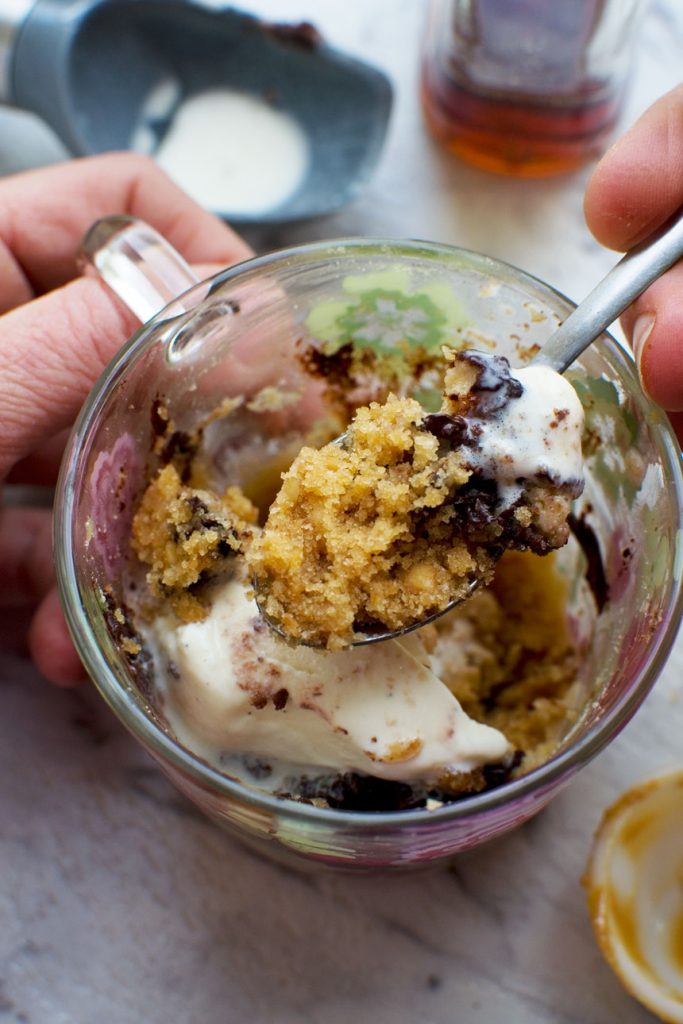 An overhead image of someone eating a 2-minute peanut butter healthy mug cake with a spoon