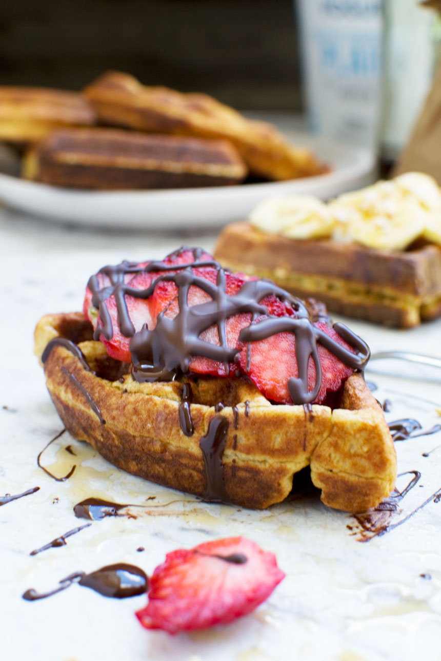 A banana bread waffle segment topped with sliced strawberries and drizzled chocolate