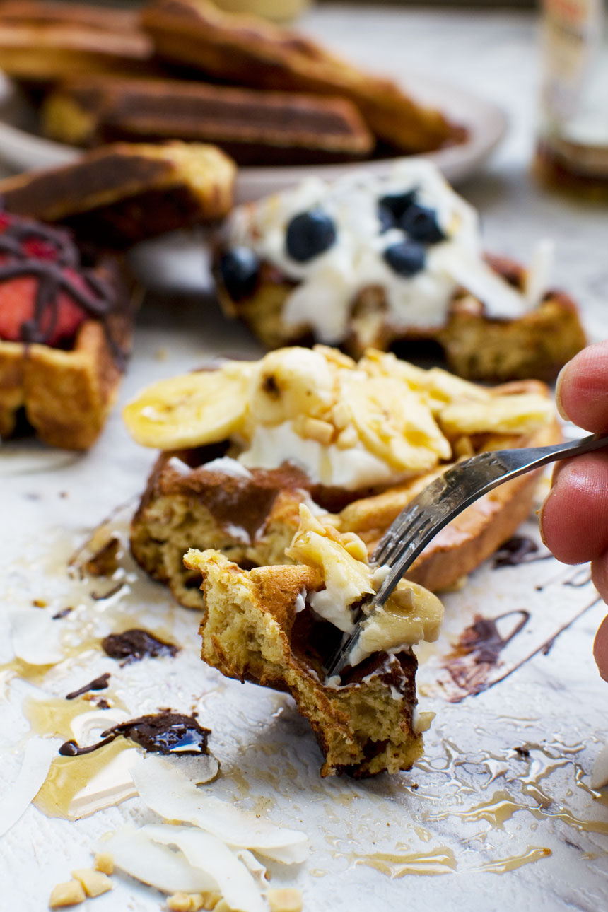 A bite of banana bread waffles on a fork, with more waffles in the background