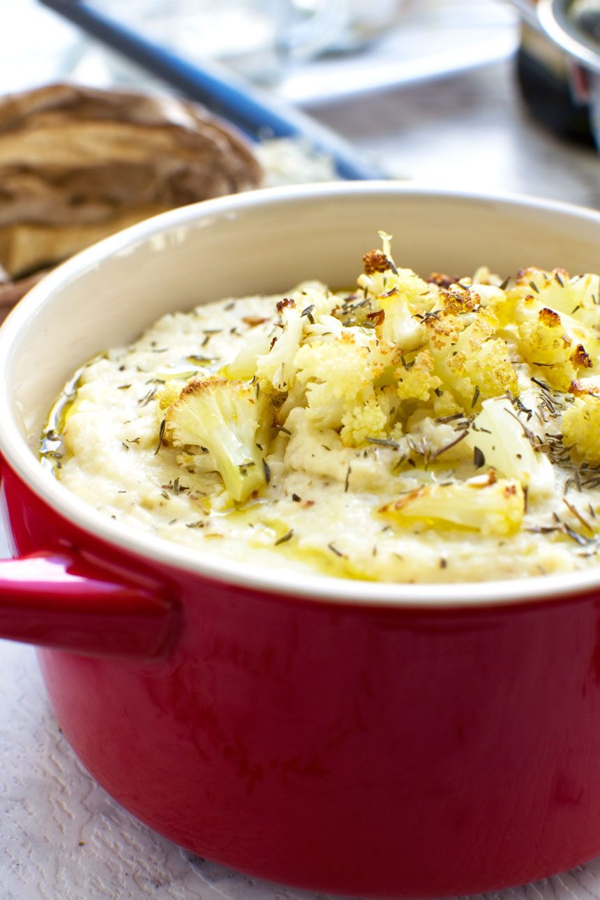 A small red cast iron pot of cauliflower and potato mashed potatoes garnished with roasted cauliflower