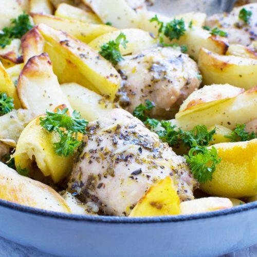 A close-up of Greek baked chicken and potatoes in a blue baking dish