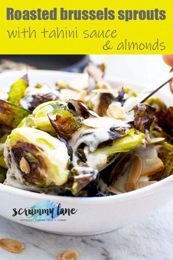 A white bowl of crispy brussels sprouts with tahini sauce and almonds