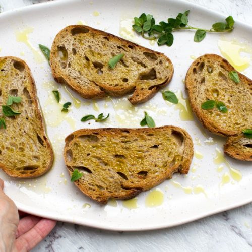 A platter of toasted bread with olive oil and salt being held