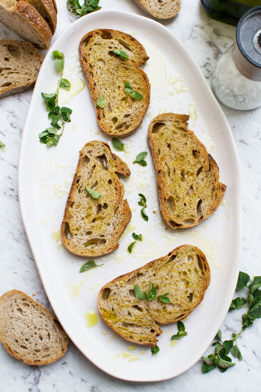 A white platter of toasted bread with olive oil and salt from above