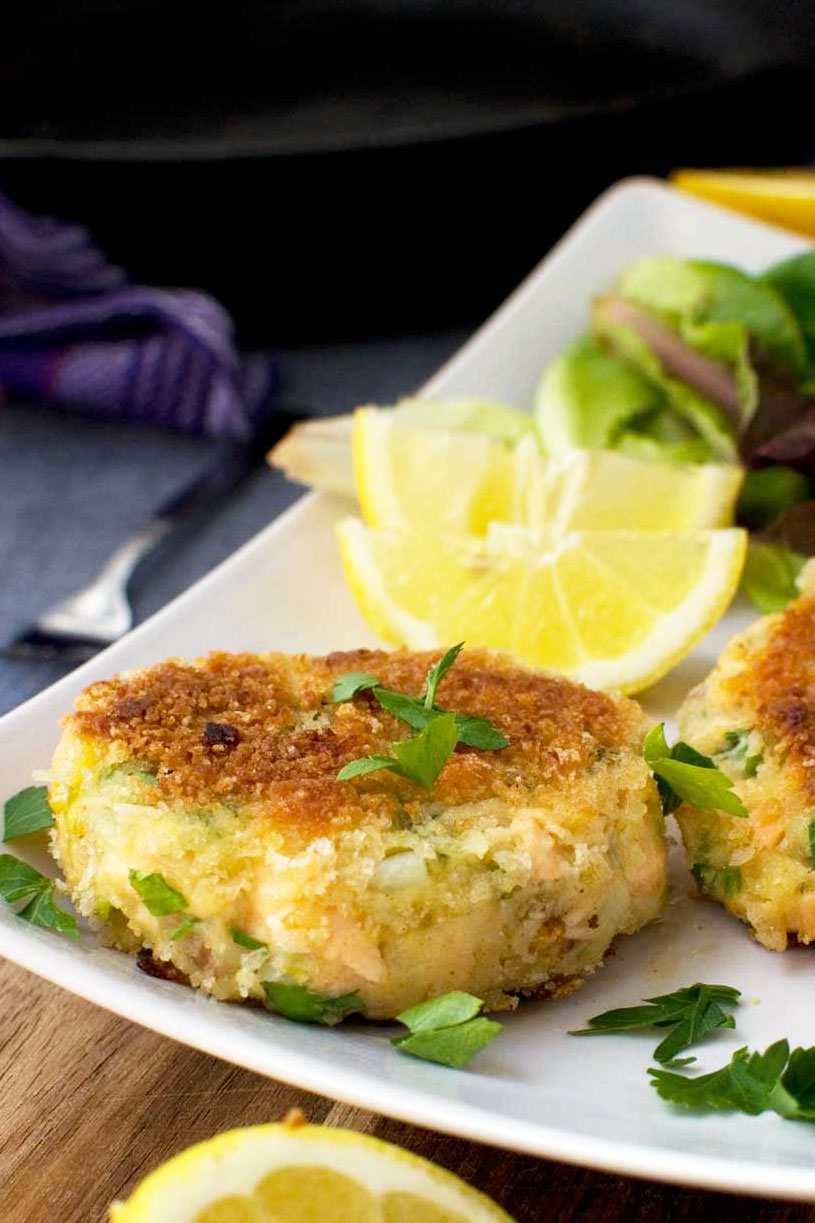 A close up of a plate of crispy salmon fish cakes with lemon