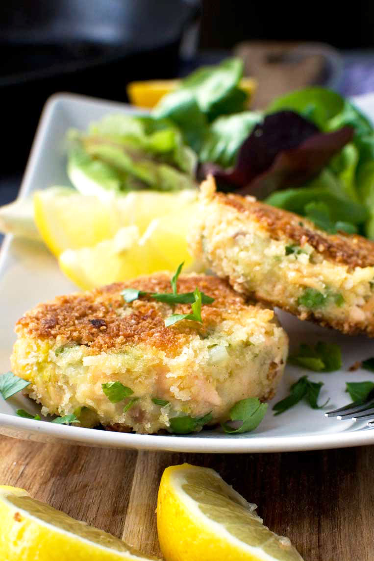 A plate of crispy salmon fish cakes with lemon and a simple salad