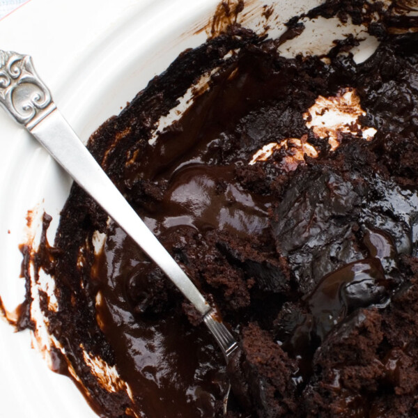 A close-up of a chocolate self saucing pudding with a decorative spoon in it