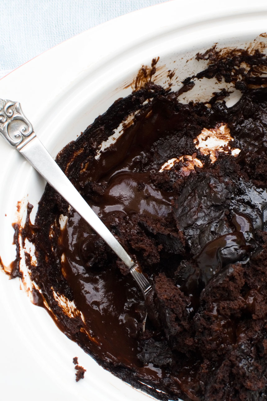 A close-up of a chocolate self saucing pudding with a decorative spoon in it