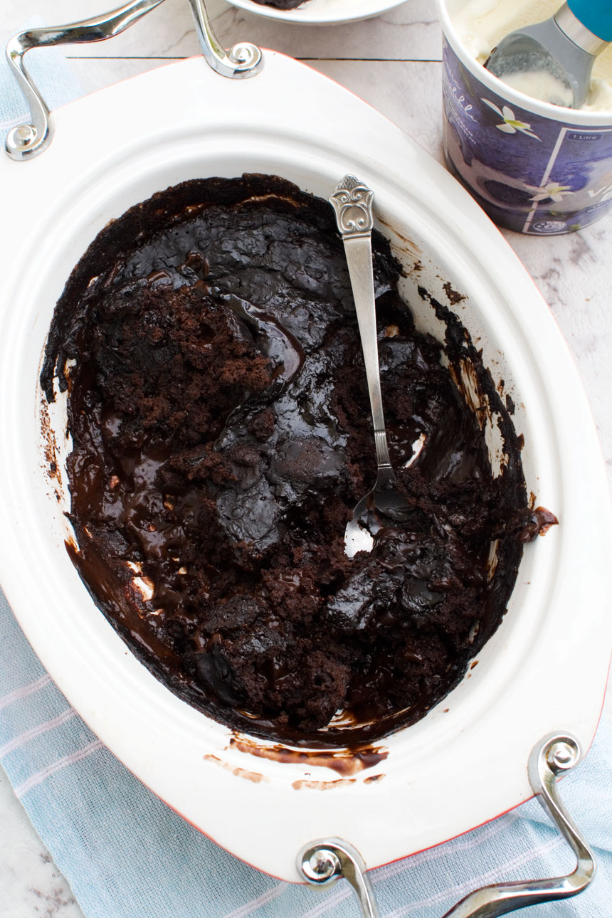 A dish of chocolate self saucing pudding with a spoon in it viewed from above