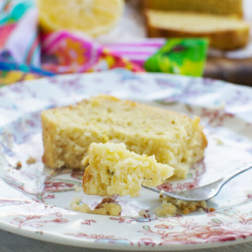 A fork of ricotta lemon loaf cake being eaten from a slice on a pink patterned plate