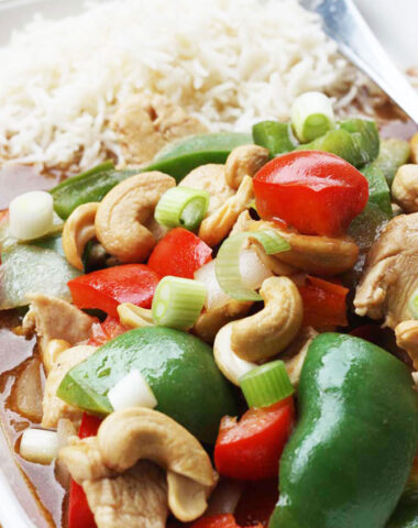 Closeup of chicken cashew nuts and peppers with rice on a rectangular white plate
