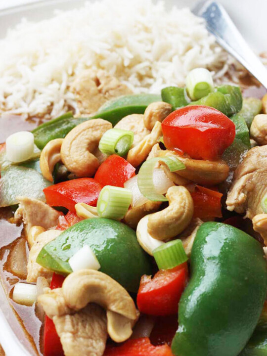 Closeup of chicken cashew nuts and peppers with rice on a rectangular white plate