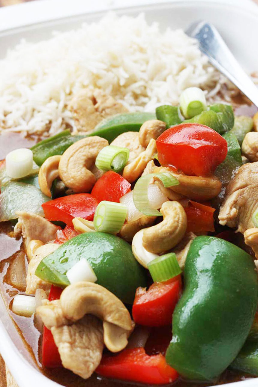 Closeup of chicken cashew nuts and peppers with rice on a rectangular white plate