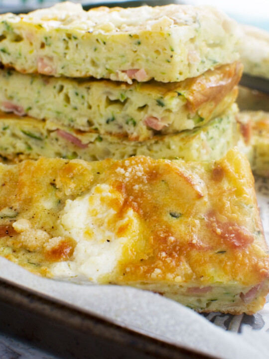 A close up of a stack of zucchini slice on a baking tray