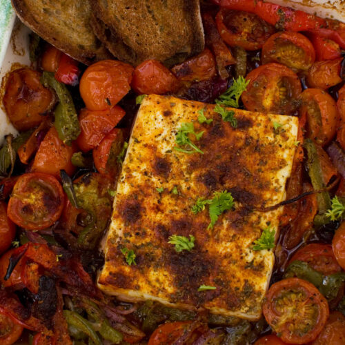 A dish of baked feta with tomatoes, peppers and olives from above