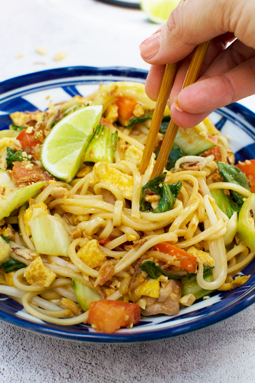 Eating a bowl of mee goreng basah or spicy Indonesian noodles with chopsticks