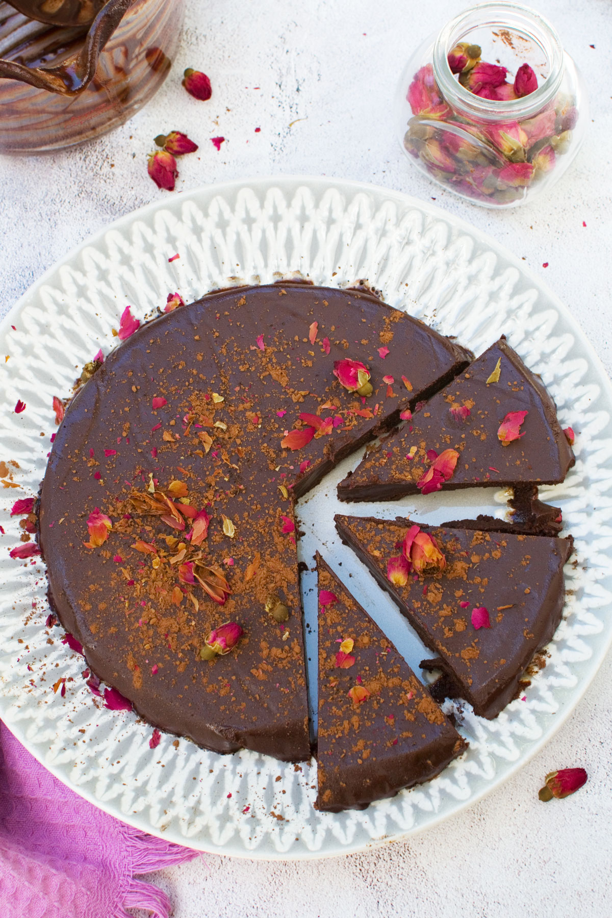 A no bake chocolate truffle cake on a grey patterned plate sliced and decorated with rose buds