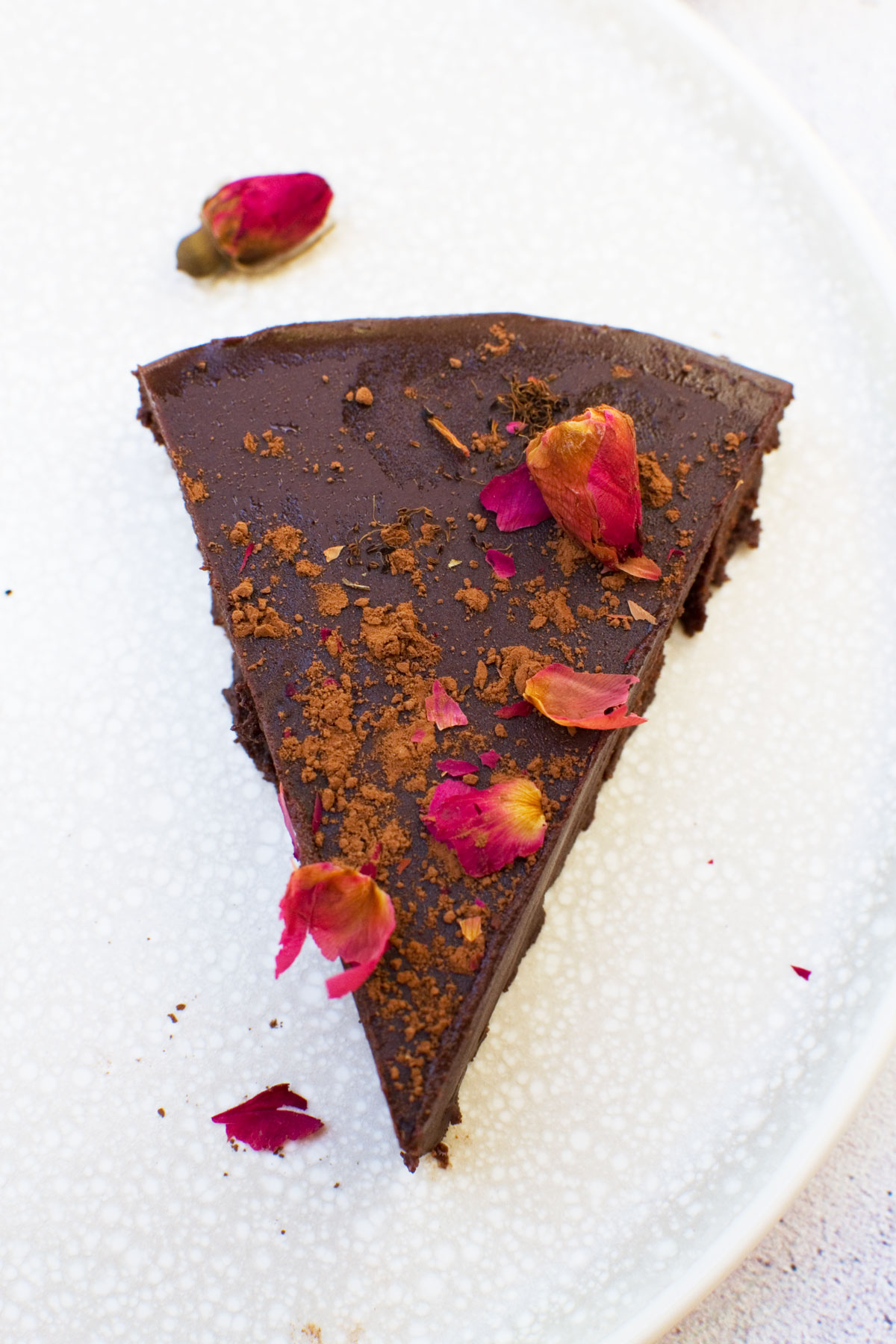 A single slice of no bake chocolate truffle cake with rose buds on top from above