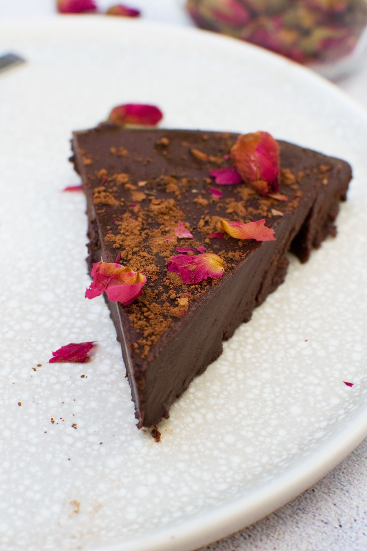 A slice of no bake chocolate truffle cake on a plate decorated with rose buds