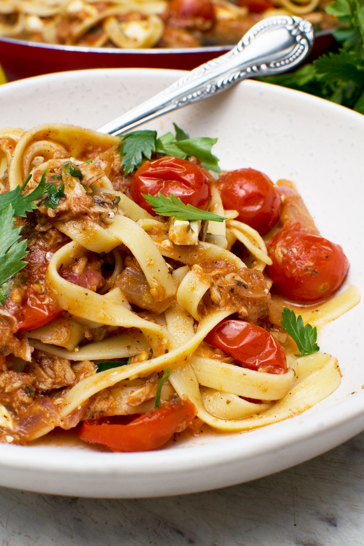 A close-up of a dish of lemony tuna spaghetti with a fork in it