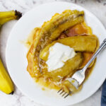 Caramelised banana pancakes with a fork and 2 bananas to the left