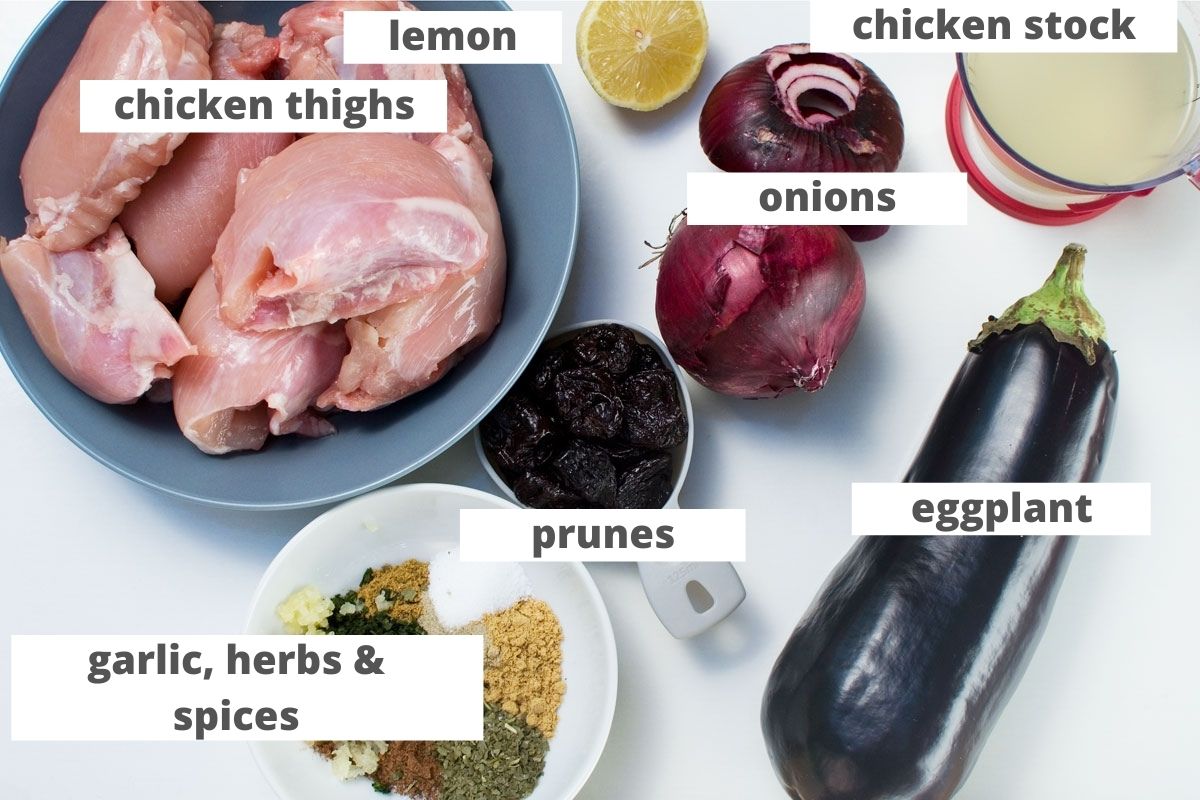 Ingredients to make a Moroccan chicken stew or chicken tagine: chicken thighs, lemon, chicken stock, onions, eggplant, prunes, and garlic, herbs and spices