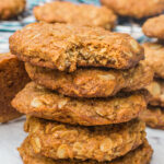 A stack of Anzac biscuits on a marble background with more scattered around