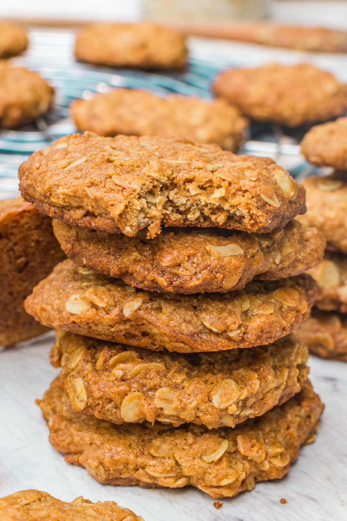 A stack of Anzac biscuits on a marble background with more scattered around