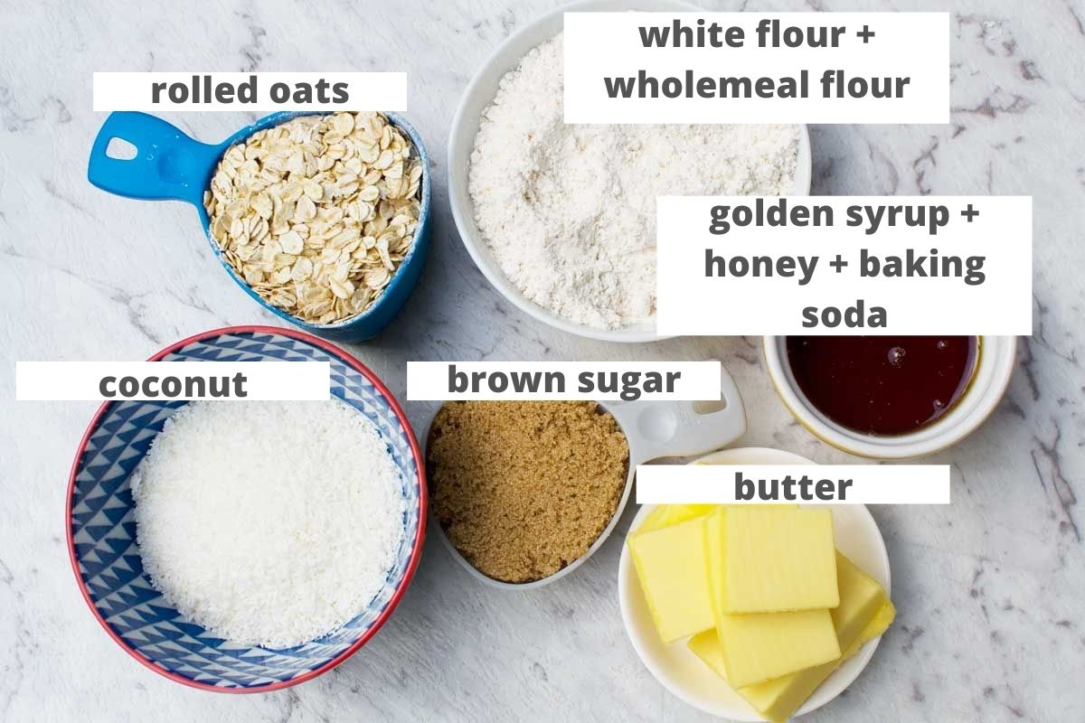 Labelled ingredients to make Anzac biscuits: rolled oats, flour, golden syrup and baking soda, coconut, brown sugar and butter