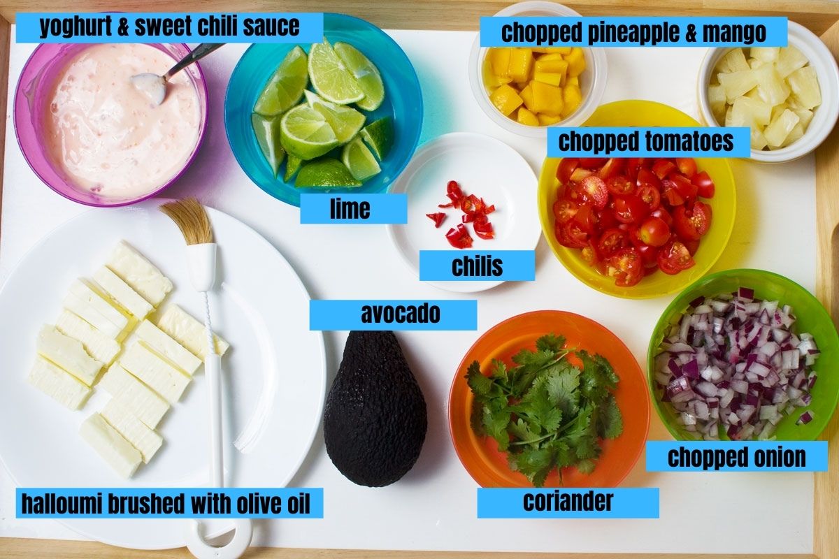 A collage of ingredients you need to make halloumi tacos including yogurt and sweet chili sauce, lime segments, pineapple, mango, chili, chopped onions, avocado, sliced halloumi, chopped tomatoes and coriander