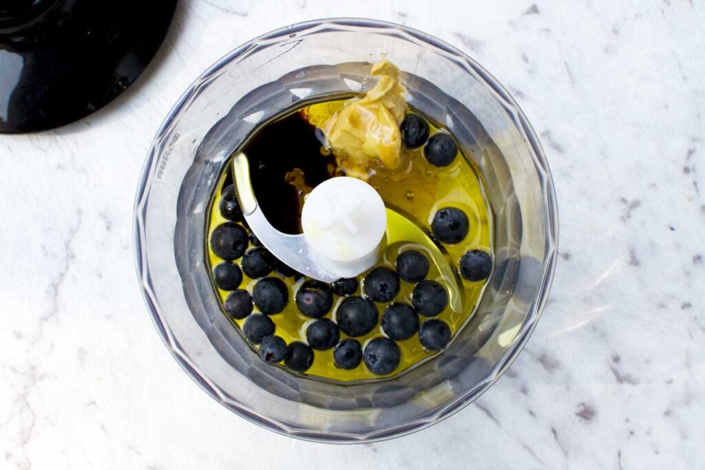 View from above of ingredients to make blueberry dressing in a small food processor