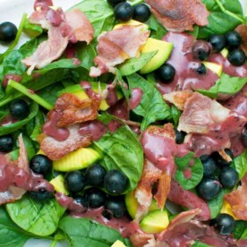 A close-up of a spinach avocado salad with blueberry vinaigrette on it