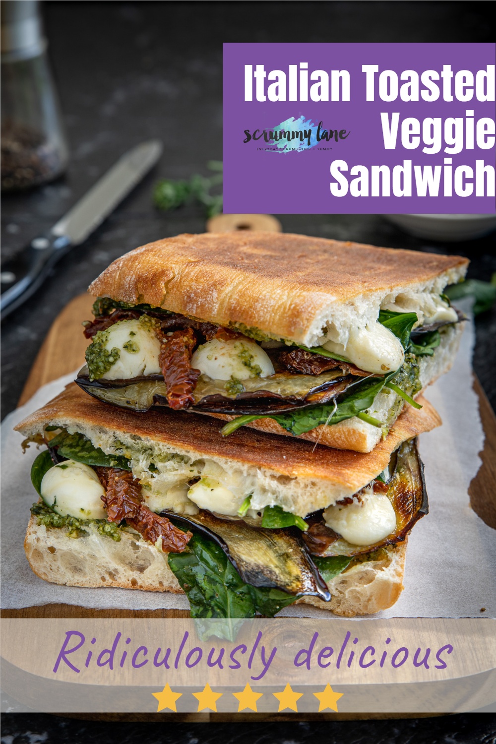 Two halves of an Italian toasted veggie sandwich on a wooden board for Pinterest with a title on it