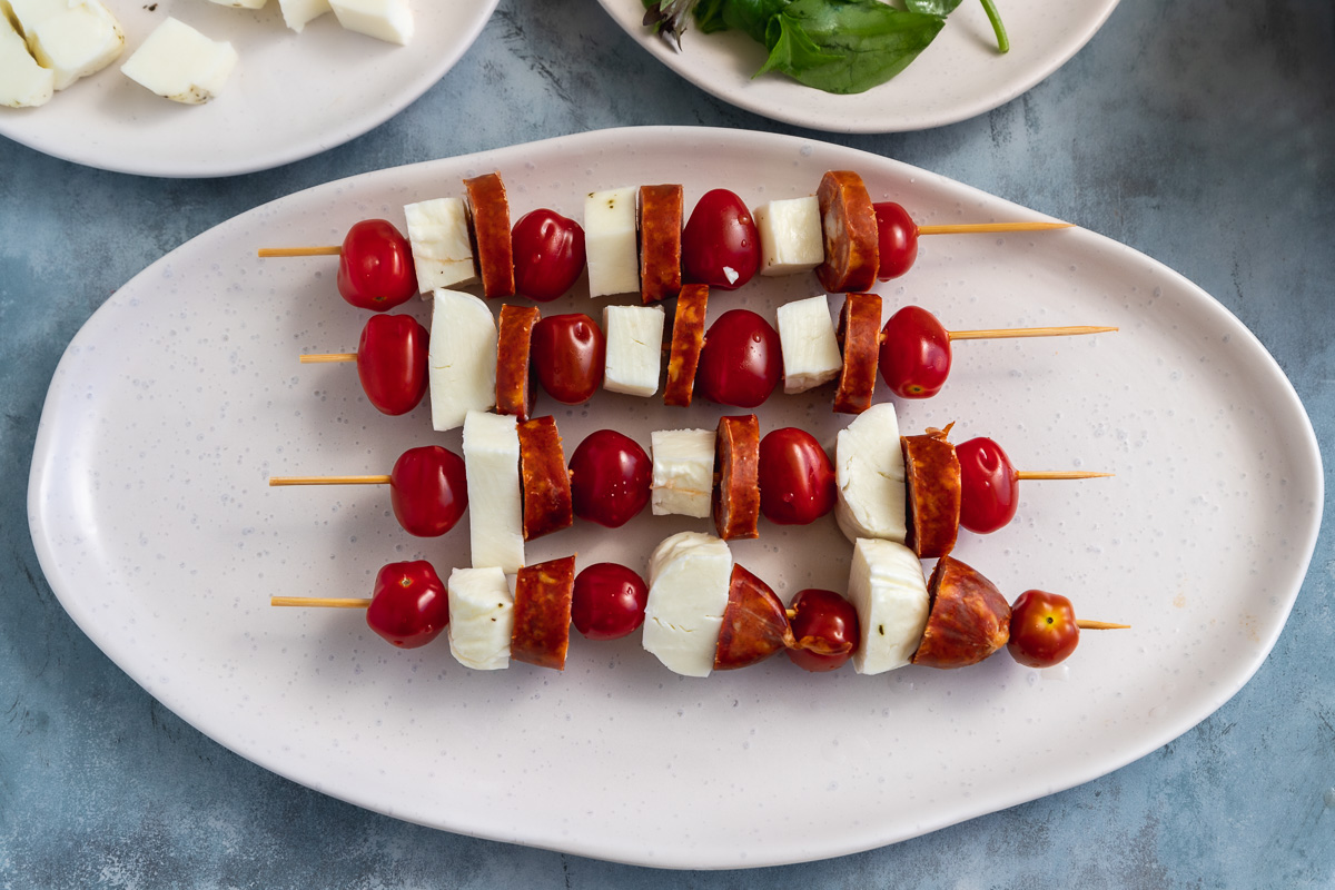 4 halloumi skewers on an oval platter before they're cooked