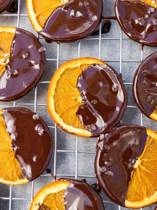 Dried orange slices dipped in chocolate and sprinkled with sea salt on a wire rack from above