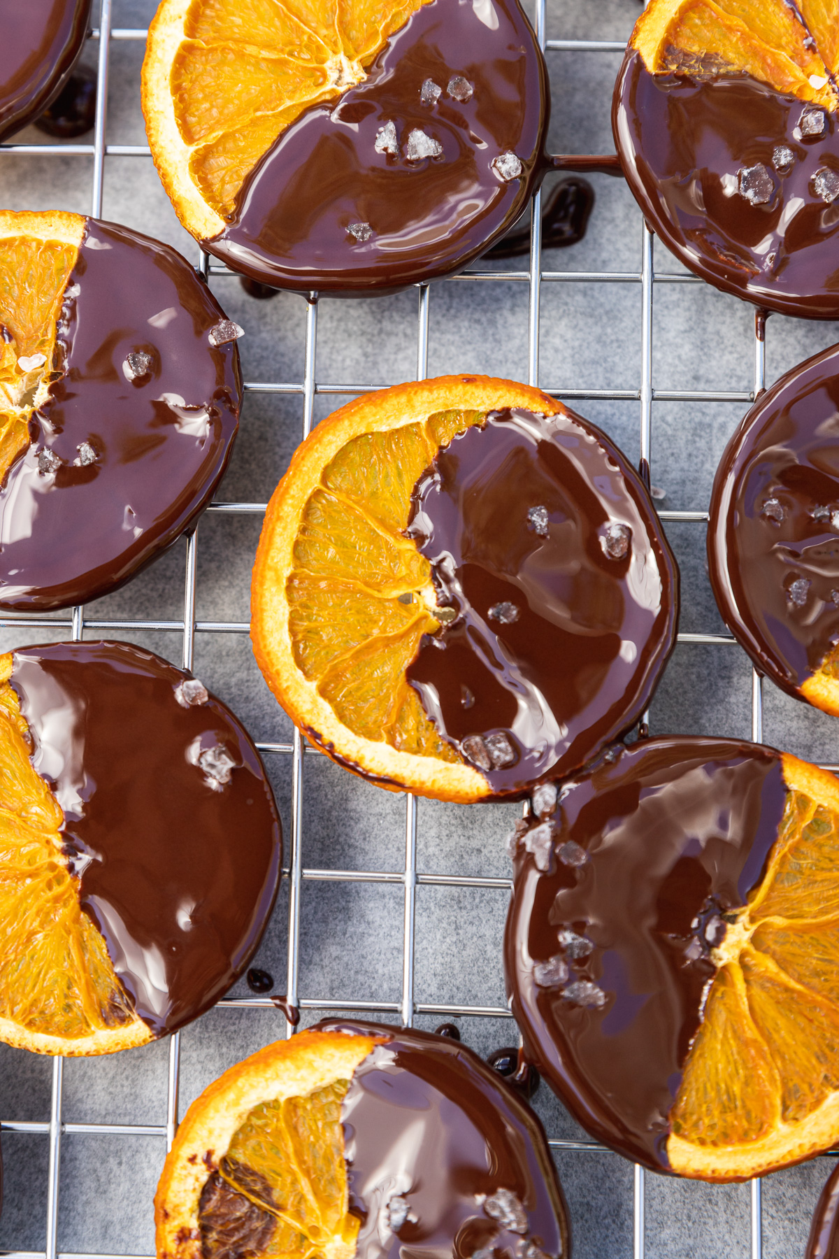 Dried orange slices dipped in chocolate and sprinkled with sea salt on a wire rack from above