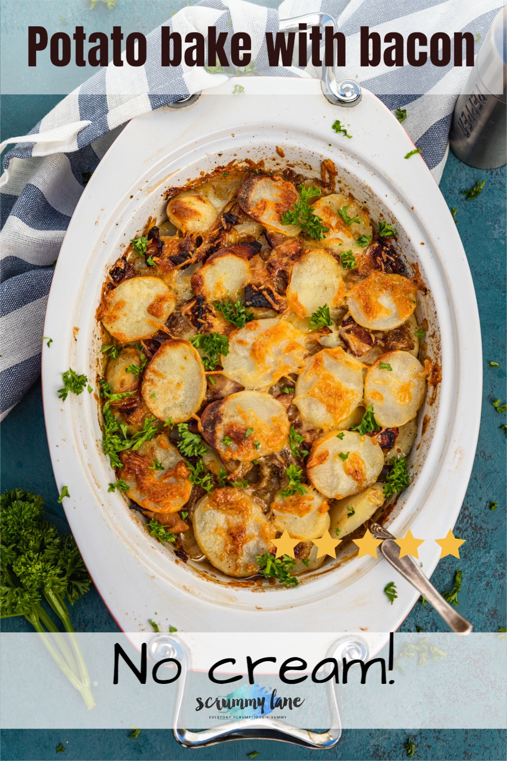 A potato bake with bacon or boulangere potatoes from above in an oval baking dish with a blue and white striped tea towel